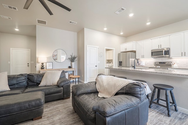 living room with ceiling fan, sink, and light hardwood / wood-style flooring