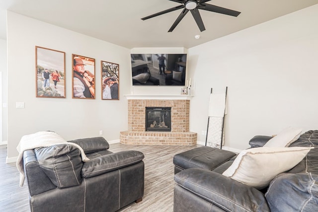 living room featuring a brick fireplace, ceiling fan, and light wood-type flooring