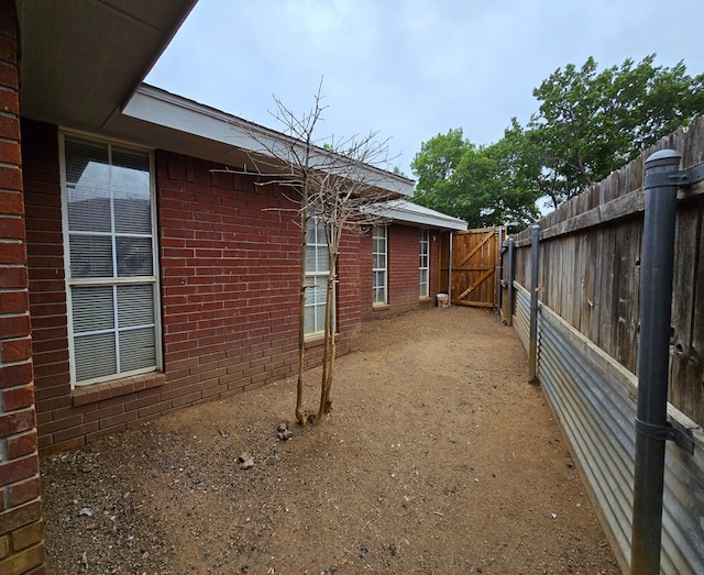 4908 Timber Ct, Midland, TX 79707 - view of side of home featuring fence, brick siding, and a gate