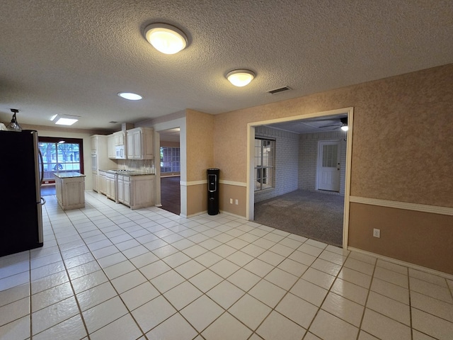 4908 Timber Ct, Midland, TX 79707 - kitchen featuring freestanding refrigerator, light tile patterned flooring, a textured ceiling, baseboards, and light countertops