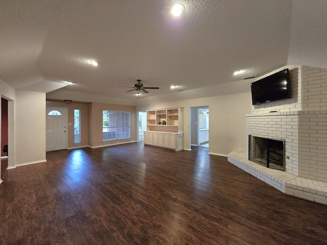 4908 Timber Ct, Midland, TX 79707 - unfurnished living room featuring a brick fireplace, a textured ceiling, ceiling fan, baseboards, and dark wood-style floors