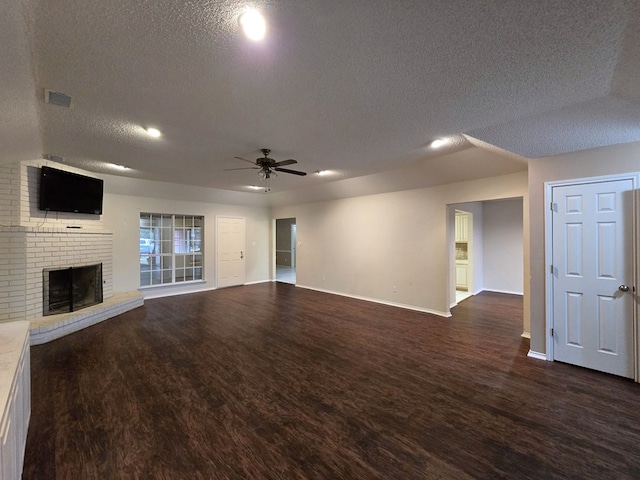 4908 Timber Ct, Midland, TX 79707 - unfurnished living room featuring a textured ceiling, baseboards, dark wood-style flooring, a ceiling fan, and a fireplace