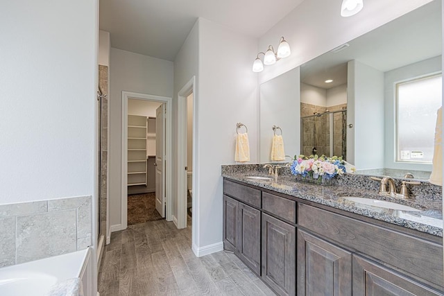 7009 Mcpherson Ln, Midland, TX 79706 - full bath featuring a stall shower, wood finished floors, double vanity, a spacious closet, and toilet