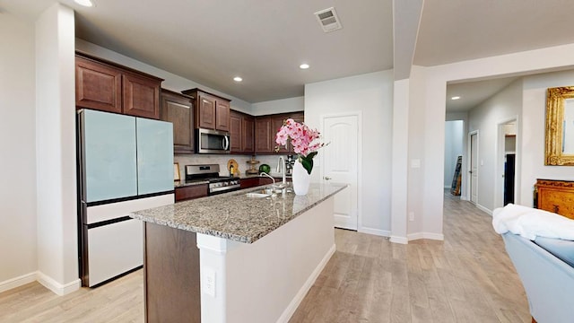 7009 Mcpherson Ln, Midland, TX 79706 - kitchen featuring stainless steel appliances, a sink, light wood-style floors, light stone counters, and recessed lighting