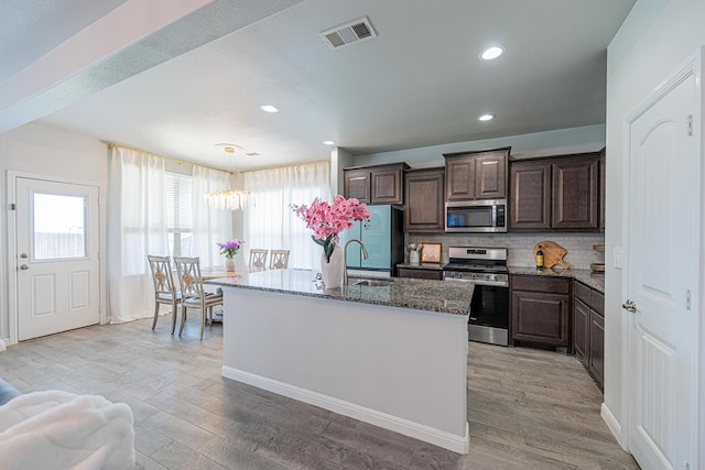 7009 Mcpherson Ln, Midland, TX 79706 - kitchen with stainless steel appliances, a chandelier, healthy amount of natural light, dark brown cabinets, and recessed lighting