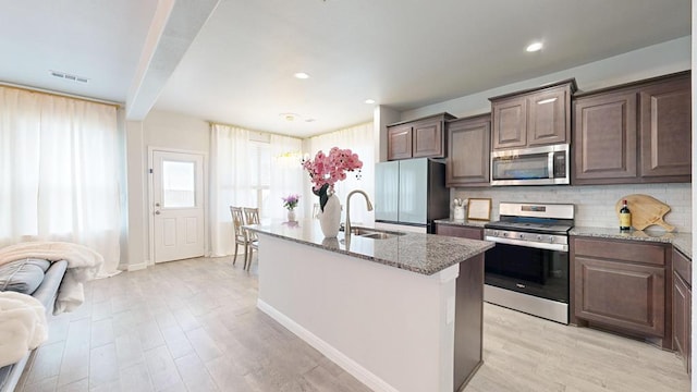 7009 Mcpherson Ln, Midland, TX 79706 - kitchen featuring stainless steel appliances, a sink, light stone countertops, tasteful backsplash, and light wood-style floors