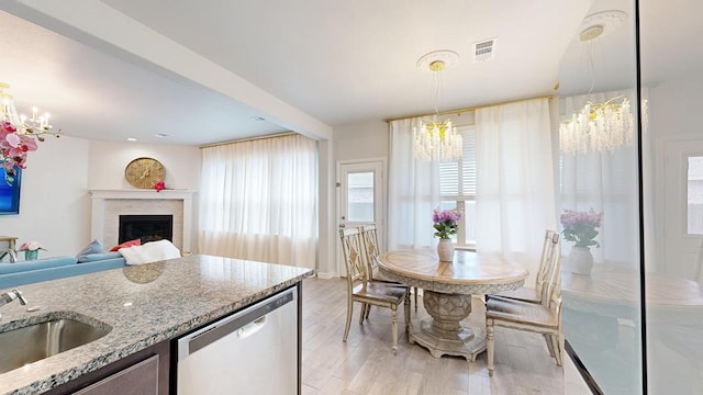 7009 Mcpherson Ln, Midland, TX 79706 - kitchen featuring a chandelier, stainless steel dishwasher, a sink, light wood finished floors, and light stone countertops