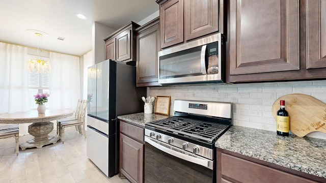7009 Mcpherson Ln, Midland, TX 79706 - kitchen with appliances with stainless steel finishes, decorative backsplash, light stone countertops, and a chandelier