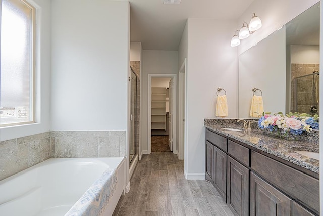 7009 Mcpherson Ln, Midland, TX 79706 - bathroom with a stall shower, a garden tub, double vanity, wood finished floors, and a spacious closet
