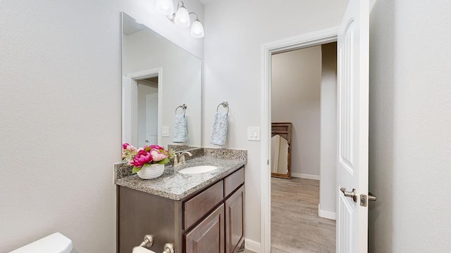 7009 Mcpherson Ln, Midland, TX 79706 - bathroom with vanity, toilet, wood finished floors, and baseboards