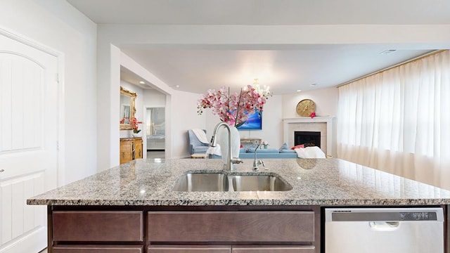 7009 Mcpherson Ln, Midland, TX 79706 - kitchen with stainless steel dishwasher, a sink, light stone counters, a center island with sink, and a fireplace