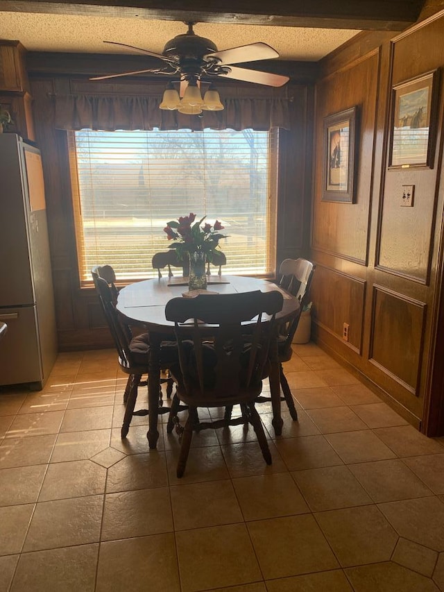 dining room featuring wooden walls, a ceiling fan, and light tile patterned flooring