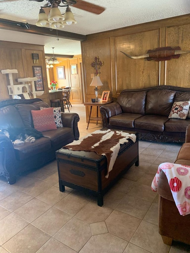 living area with light tile patterned floors, wooden walls, a textured ceiling, and a ceiling fan