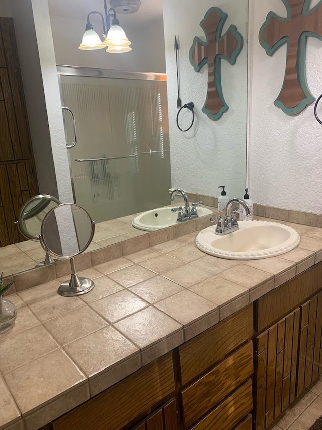 full bath with a textured wall, a notable chandelier, a shower stall, and vanity