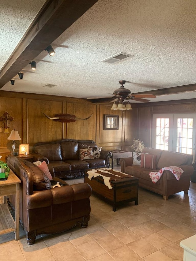 living area featuring light tile patterned floors, a textured ceiling, visible vents, and a ceiling fan