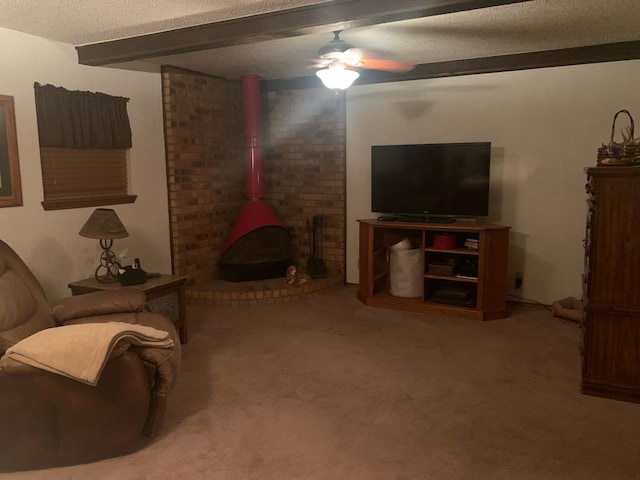 carpeted living area with a ceiling fan, a wood stove, a textured ceiling, and beam ceiling