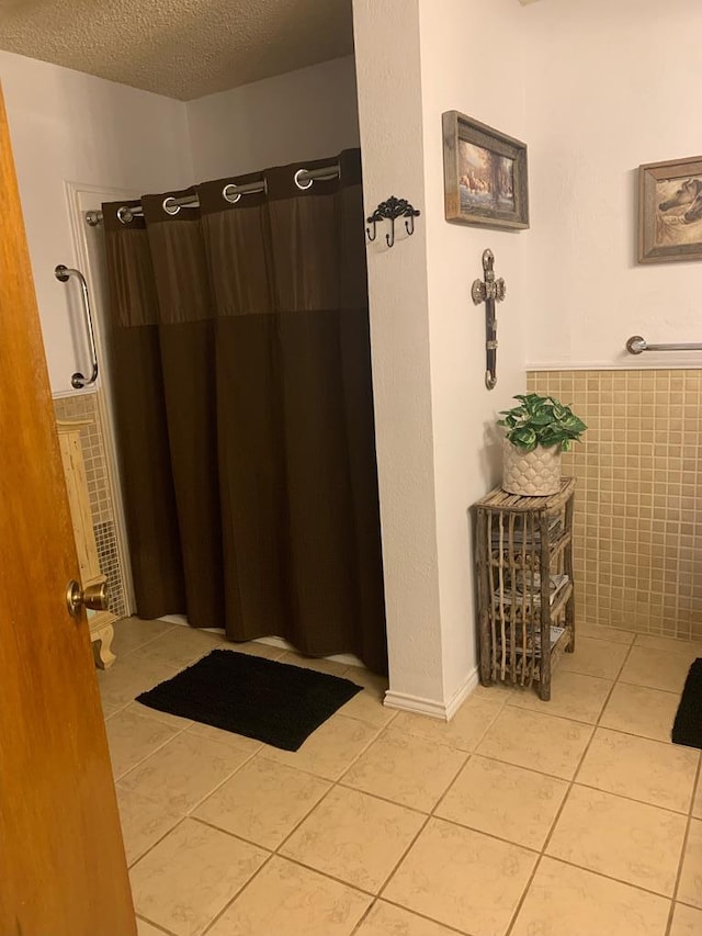 full bath featuring a shower with curtain, tile walls, a textured ceiling, and tile patterned floors