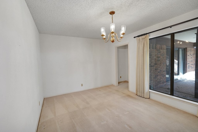 empty room featuring light carpet, a notable chandelier, and a textured ceiling