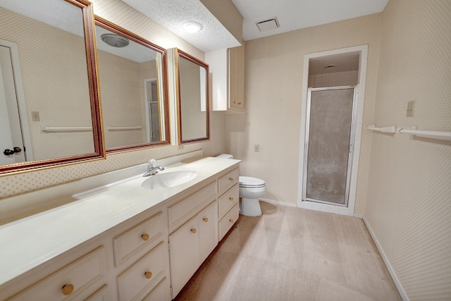 bathroom with vanity, a shower with door, toilet, and a textured ceiling