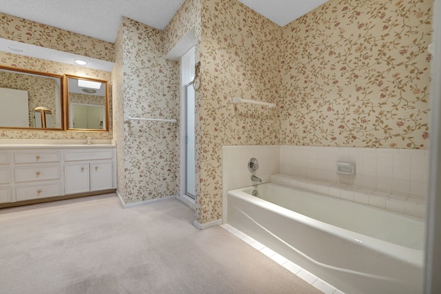 bathroom featuring vanity, a tub to relax in, and a textured ceiling