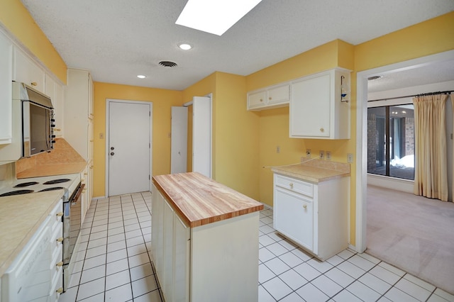 kitchen featuring white cabinetry, a center island, electric stove, and a textured ceiling