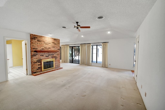 unfurnished living room featuring lofted ceiling, ceiling fan, a fireplace, a textured ceiling, and light colored carpet