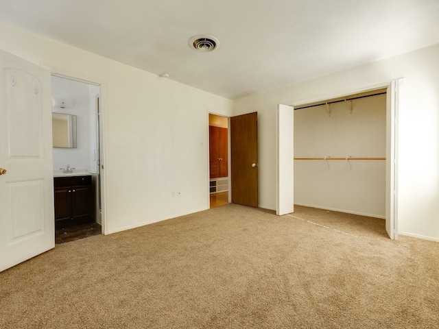 unfurnished bedroom with connected bathroom, light carpet, and a closet