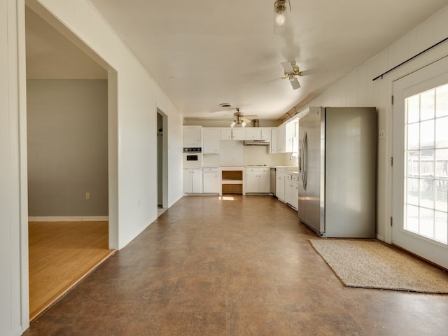 kitchen with white cabinetry, plenty of natural light, white oven, and stainless steel fridge