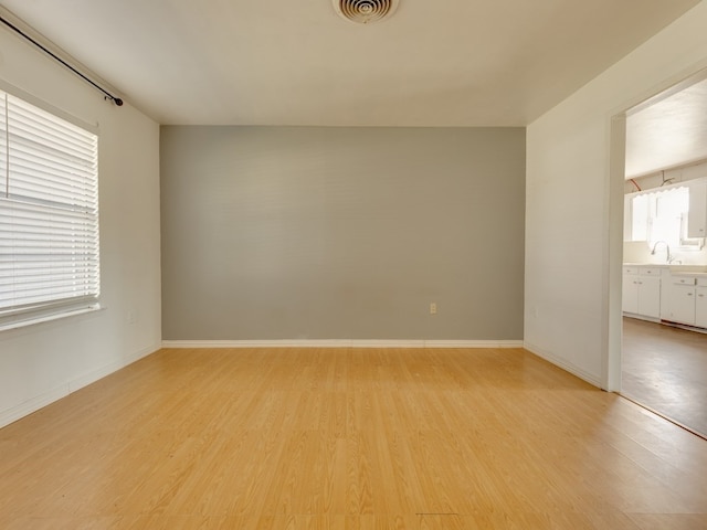 spare room featuring sink and light hardwood / wood-style flooring