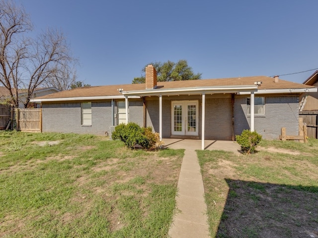 back of property featuring french doors, a patio, and a lawn