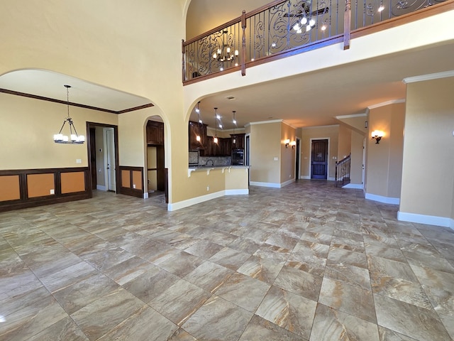 unfurnished living room with ornamental molding and a towering ceiling