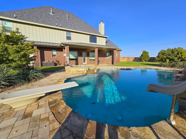 view of swimming pool featuring a patio, a pool with connected hot tub, central AC unit, a water slide, and fence