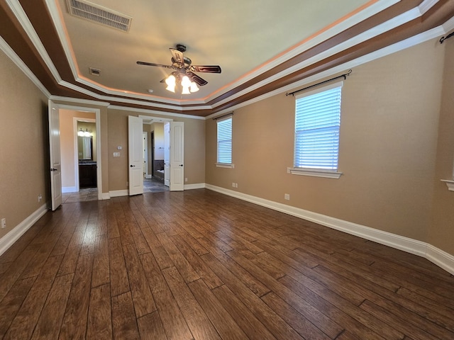 spare room featuring ceiling fan, ornamental molding, dark wood-type flooring, and a tray ceiling