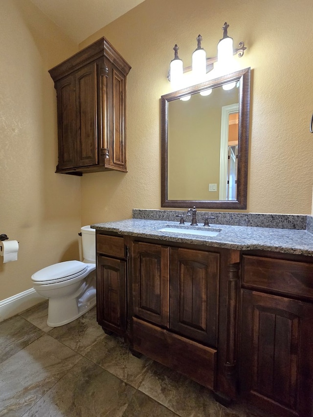 bathroom with vanity, toilet, and baseboards