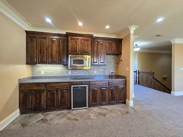 kitchen featuring backsplash, dark brown cabinetry, beverage cooler, crown molding, and stainless steel microwave