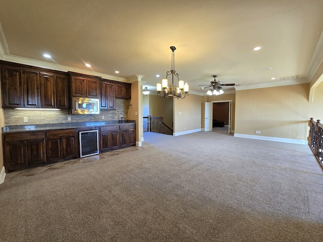 kitchen with pendant lighting, stainless steel microwave, wine cooler, tasteful backsplash, and dark brown cabinets