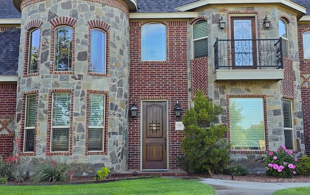 5416 Alysheba, Midland, TX 79705 - view of front of home featuring a balcony, a shingled roof, stone siding, and brick siding
