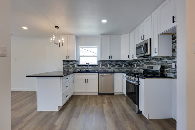 kitchen featuring stainless steel appliances, a peninsula, dark countertops, decorative backsplash, and recessed lighting