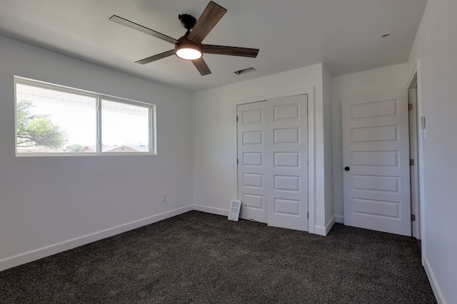 unfurnished bedroom featuring dark colored carpet, baseboards, and ceiling fan