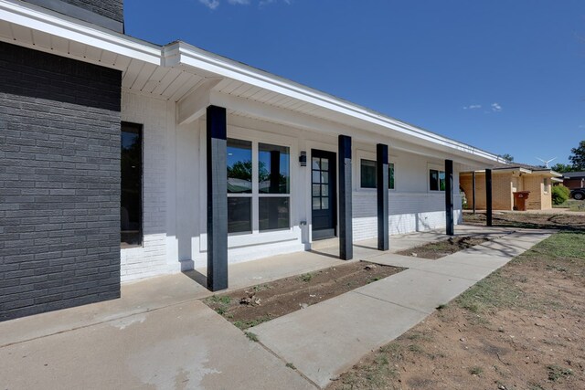 entrance to property featuring brick siding and a porch