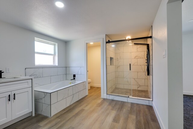 bathroom featuring toilet, wood finished floors, a bath, a stall shower, and recessed lighting