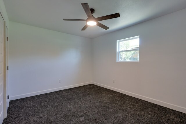 spare room with ceiling fan, dark carpet, and baseboards