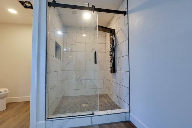 full bath featuring toilet, wood finished floors, a shower stall, and baseboards