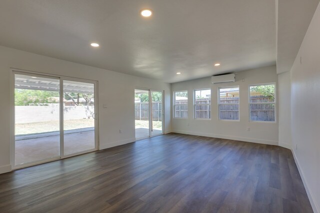 spare room featuring baseboards, dark wood finished floors, recessed lighting, and a wall mounted AC