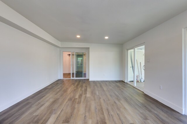 spare room featuring recessed lighting, wood finished floors, and baseboards