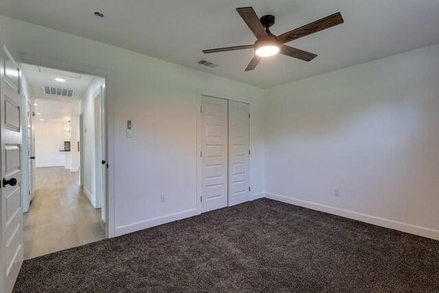 unfurnished bedroom with attic access, light colored carpet, a closet, and baseboards