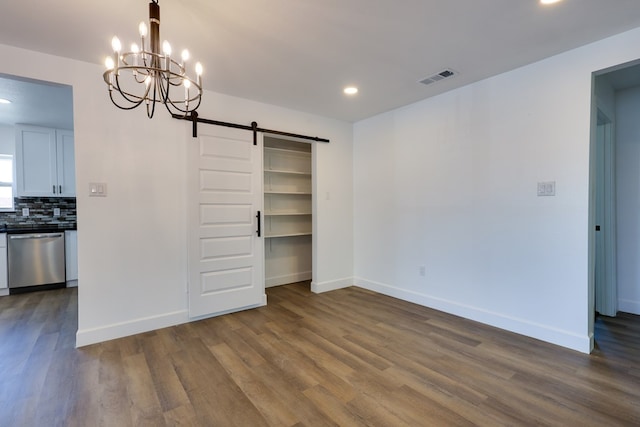 unfurnished bedroom with a barn door, dark wood-style flooring, a chandelier, baseboards, and recessed lighting