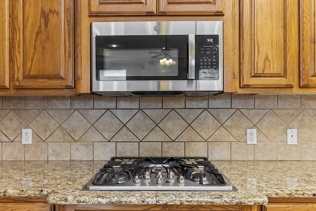 4906 Crista Ln, Midland, TX 79707 - kitchen featuring appliances with stainless steel finishes, brown cabinetry, and decorative backsplash