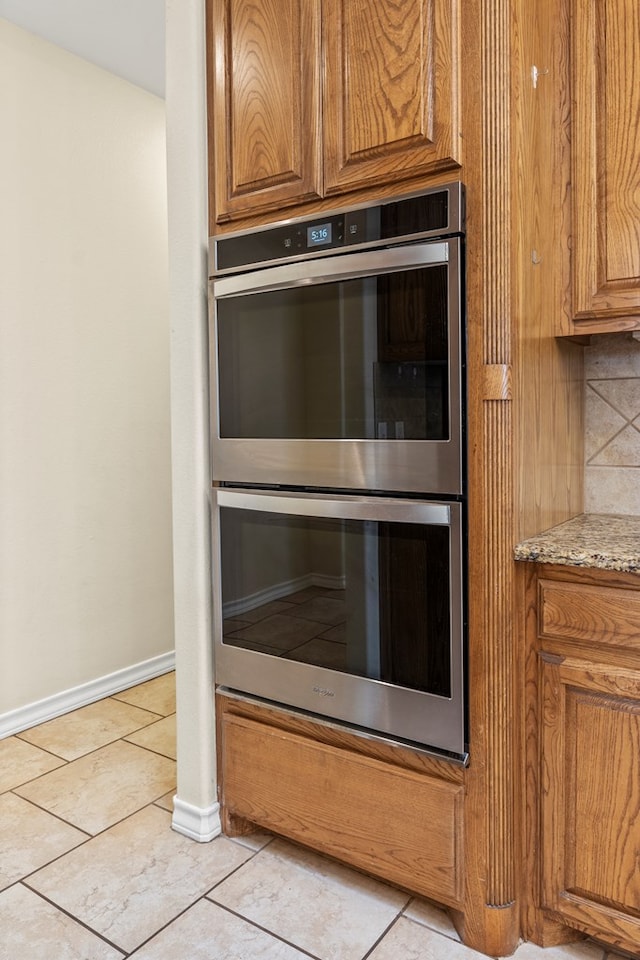 4906 Crista Ln, Midland, TX 79707 - kitchen view of double oven, brown cabinets, tasteful backsplash, and light stone countertops
