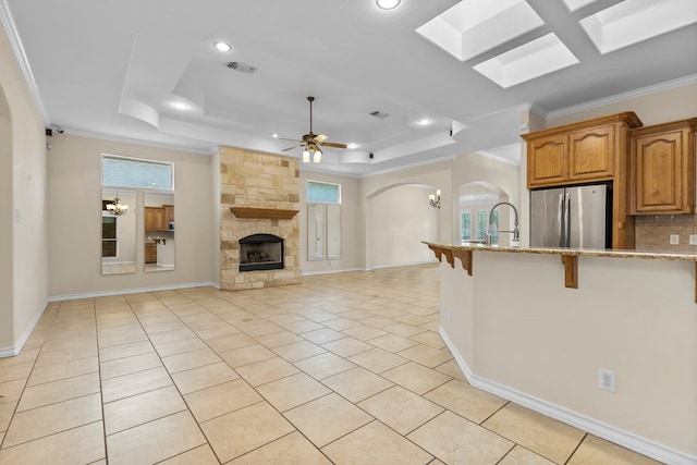 4906 Crista Ln, Midland, TX 79707 - kitchen featuring freestanding refrigerator, a tray ceiling, a breakfast bar, arched walkways, and light stone countertops